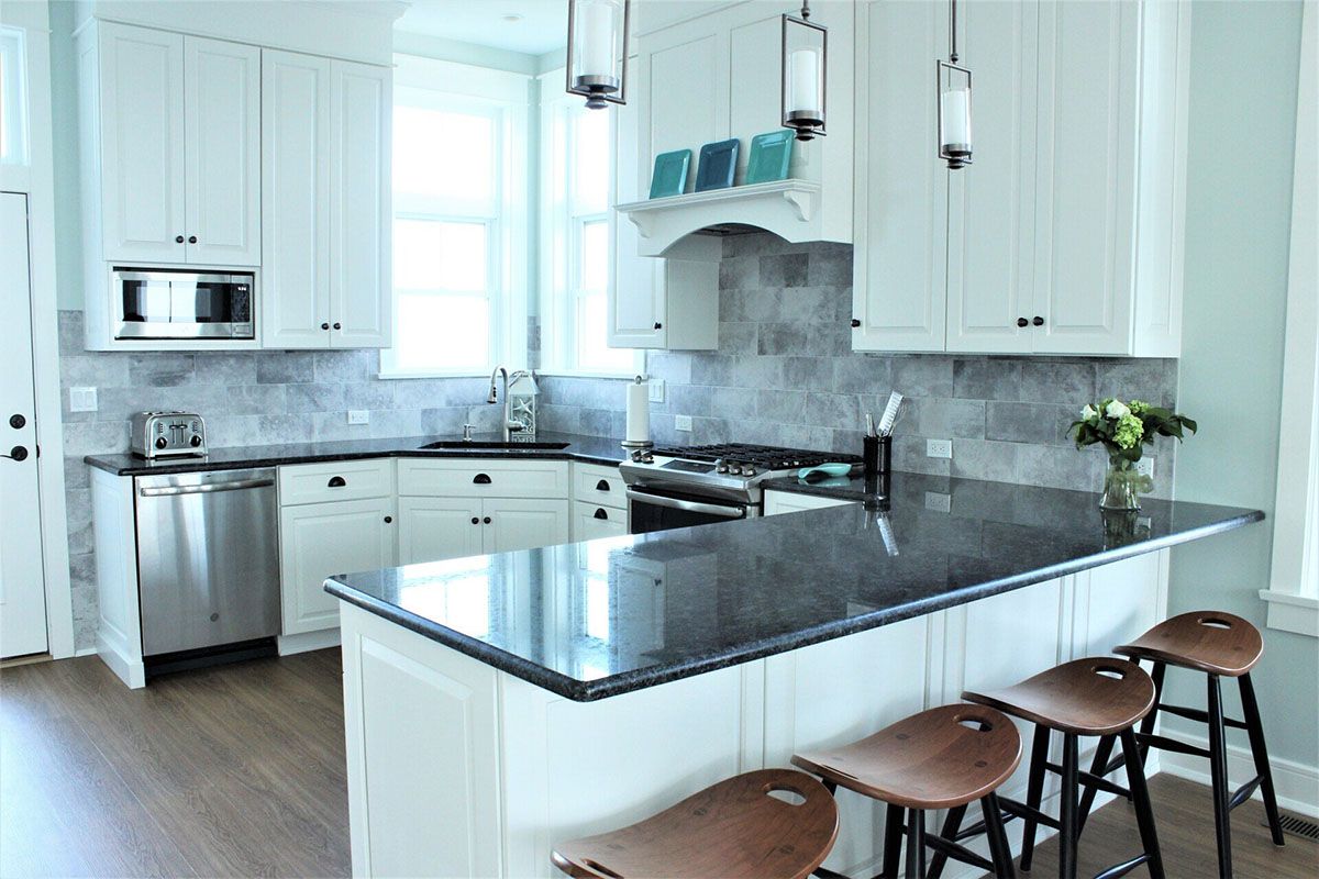 A kitchen with white cabinets and a black granite countertop