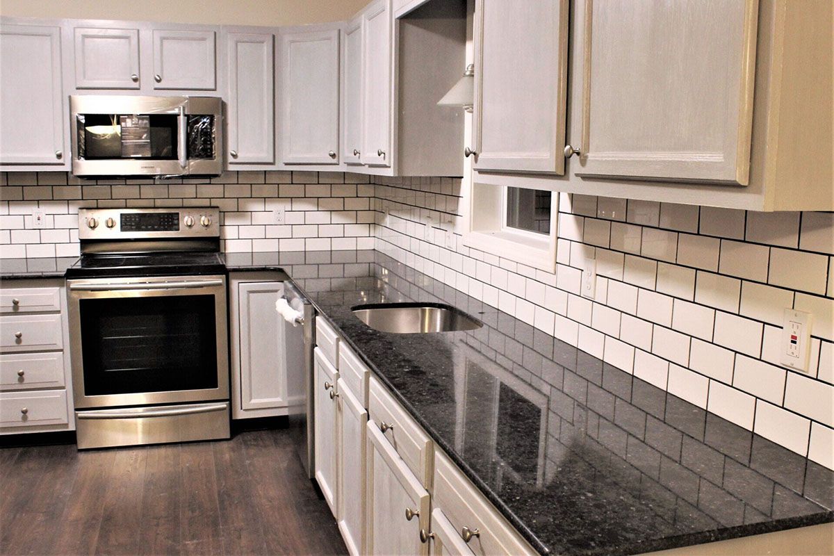 A kitchen with white cabinets, stainless steel appliances, granite countertops, and a stove