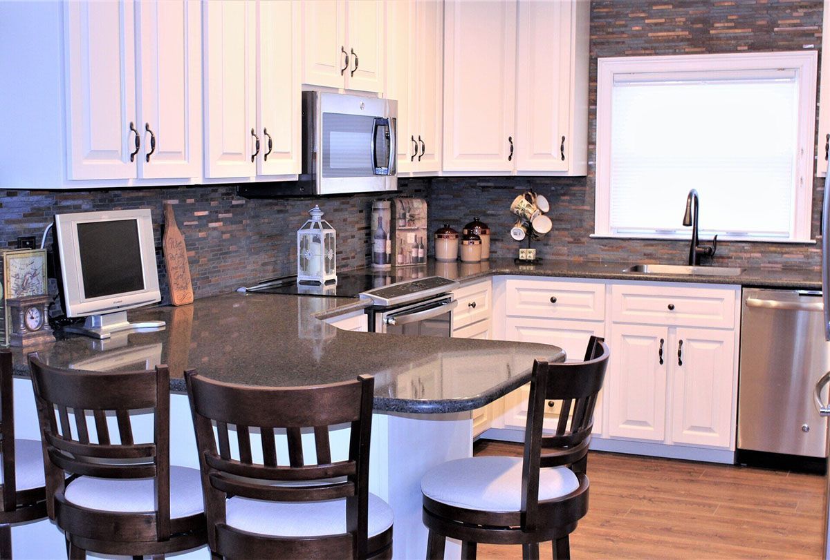 A kitchen with white cabinets, stainless steel appliances, granite countertops, and a large island