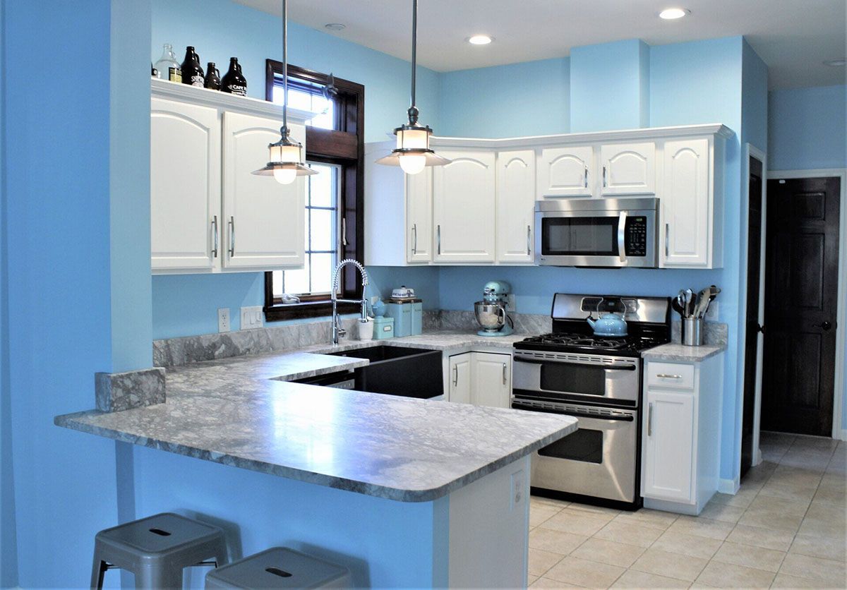 A kitchen with blue walls, white cabinets, and stainless steel appliances