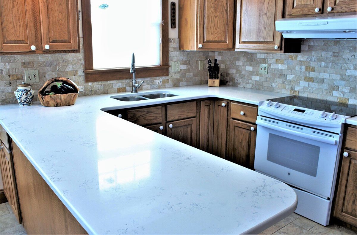 A kitchen with wooden cabinets, white counter tops, a stove, and a sink