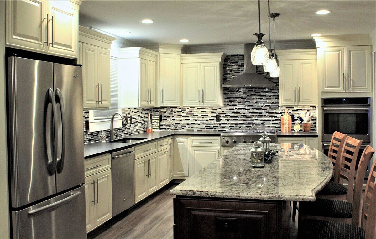 A kitchen with white cabinets, stainless steel appliances, granite countertops, and a large island