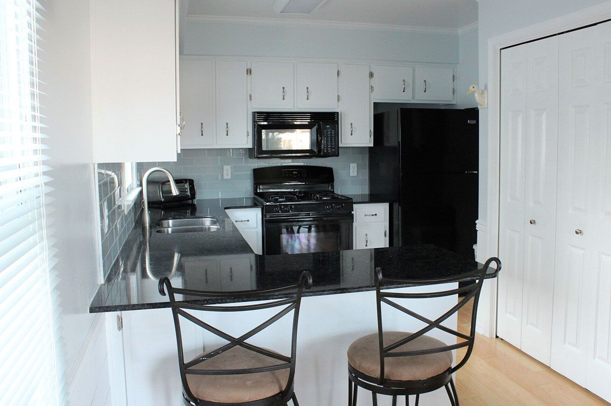 A kitchen with black granite countertops and white cabinets
