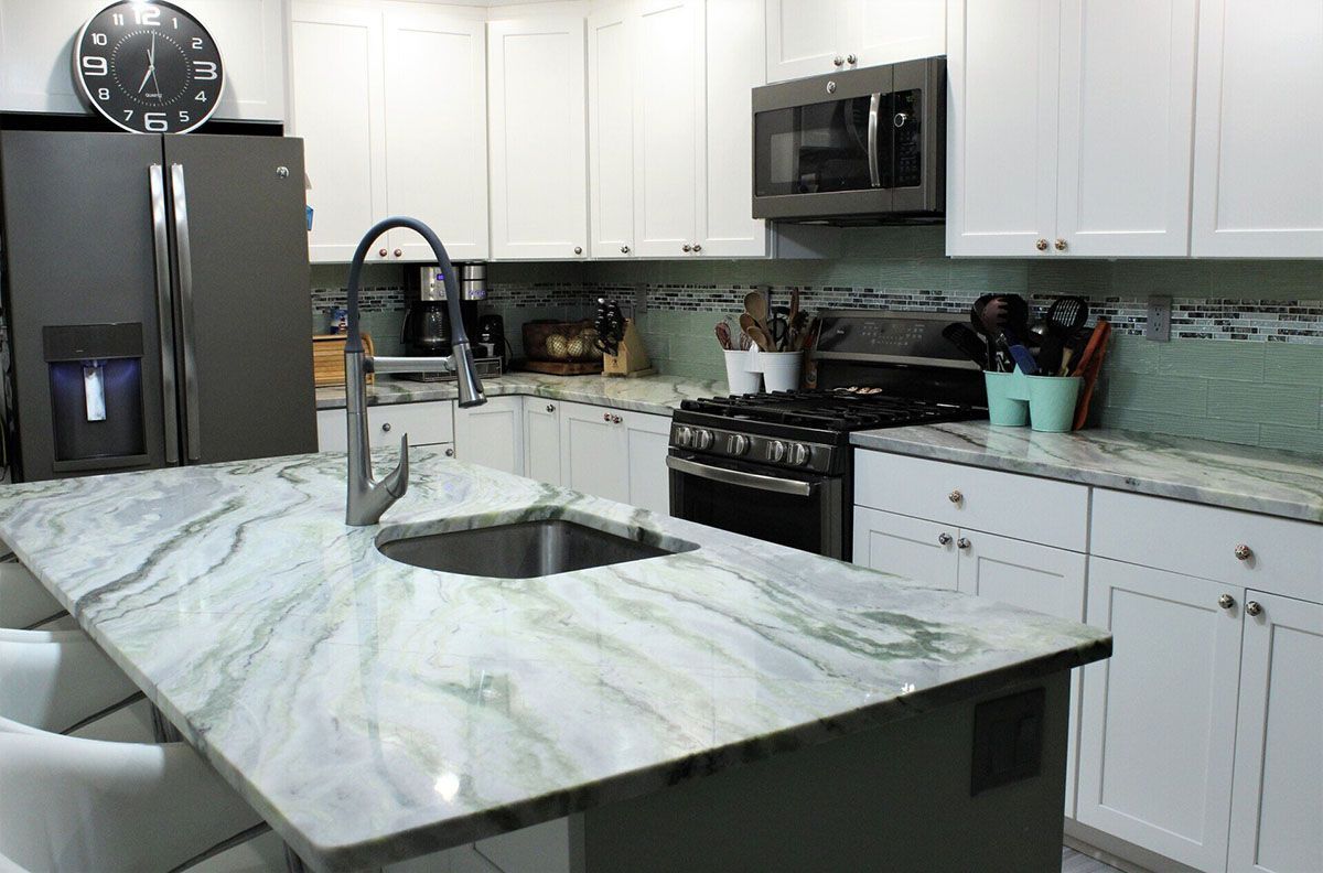 A kitchen with white cabinets, granite countertops, and stainless steel appliances