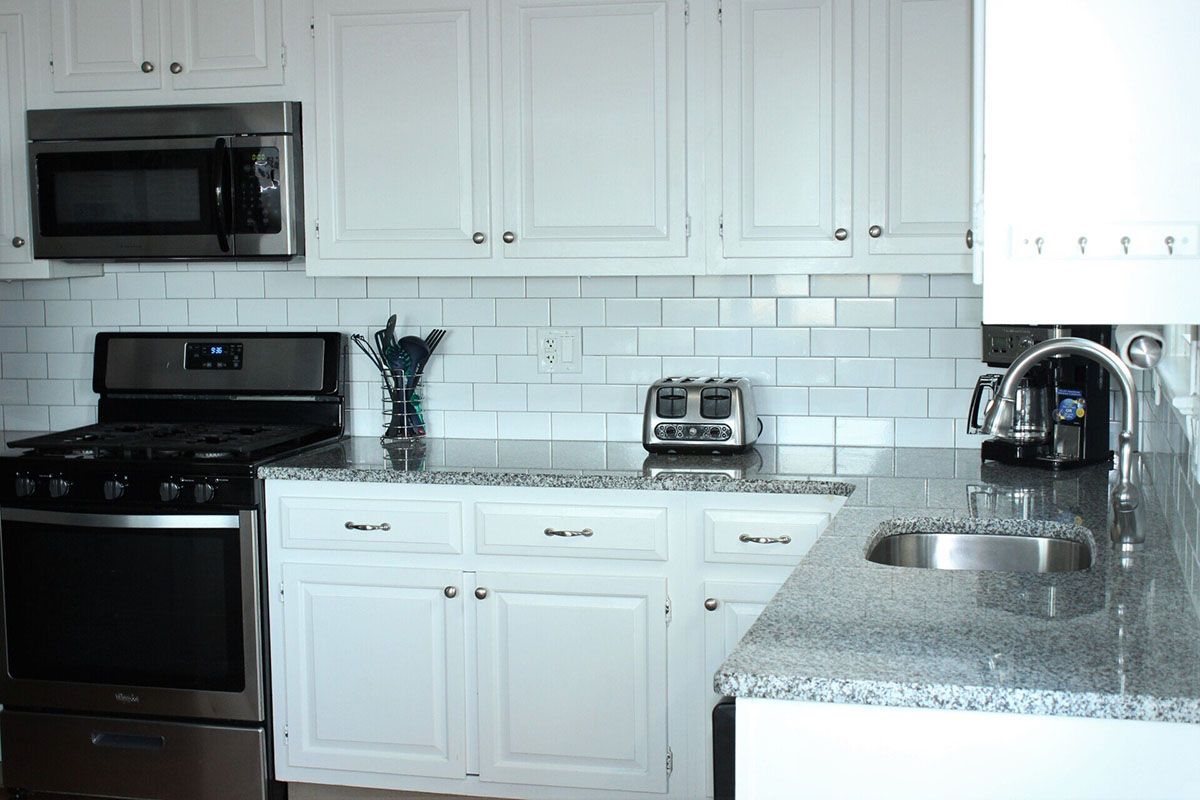 A kitchen with white cabinets and stainless steel appliances