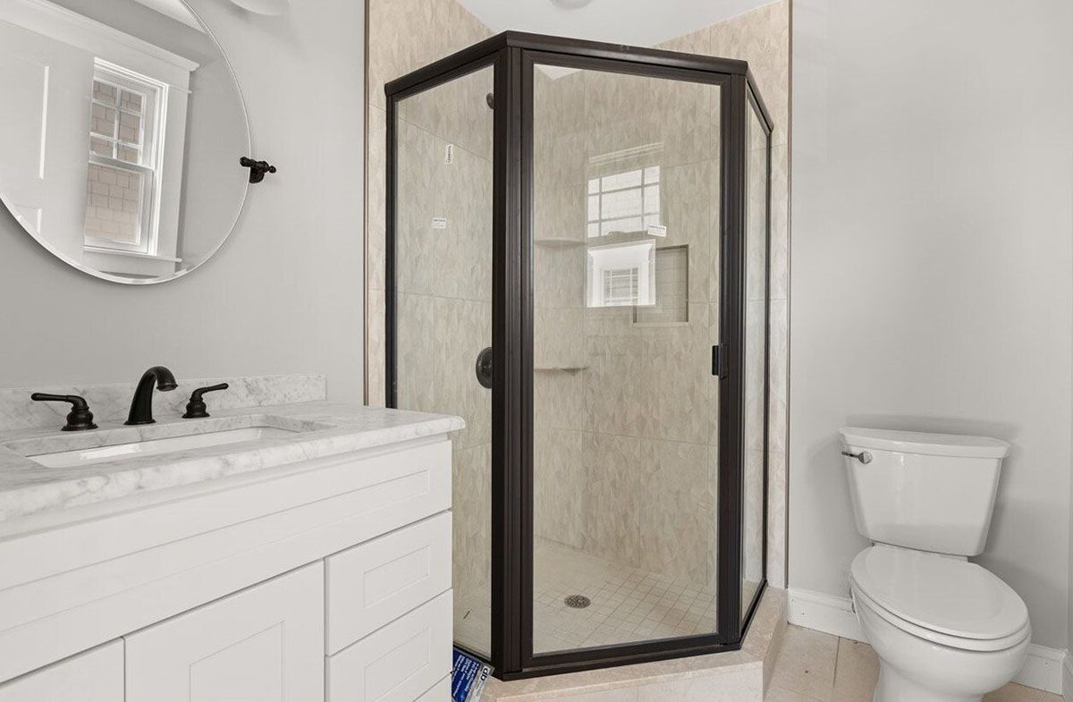 A bathroom with a shower, toilet, sink, and mirror