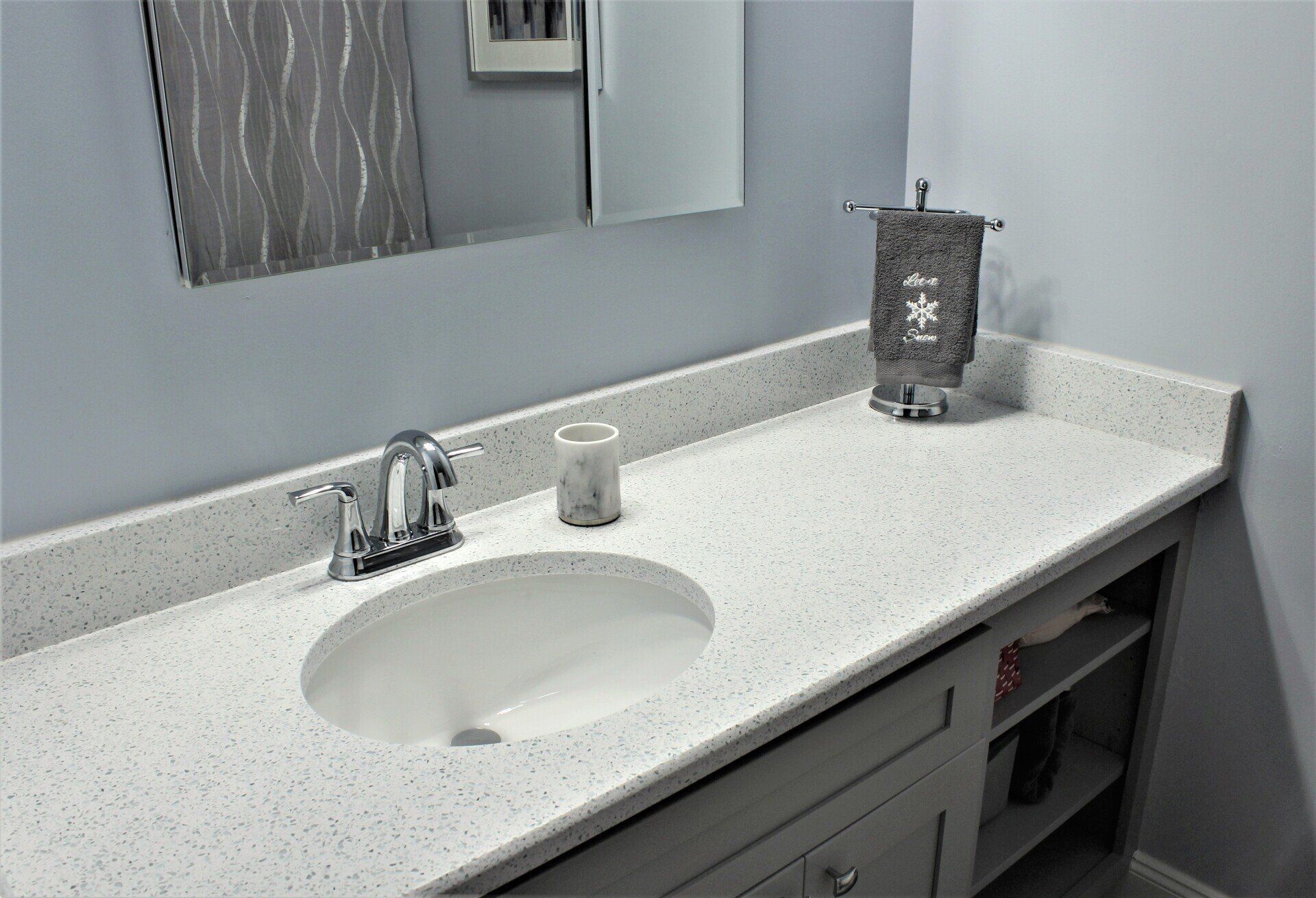 A bathroom with a sink , mirror and towel rack.