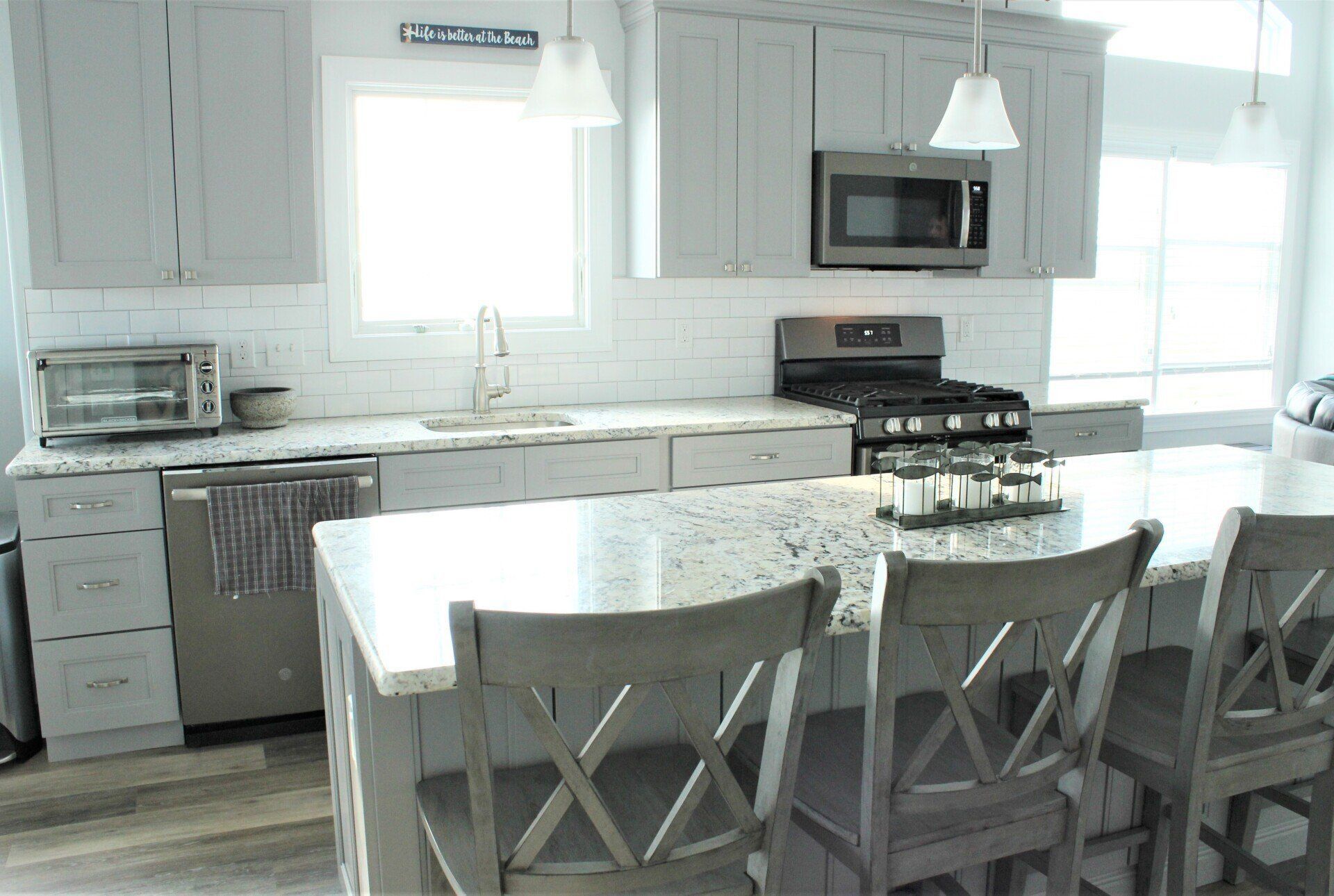 A kitchen with white cabinets , stainless steel appliances , granite counter tops and a large island.