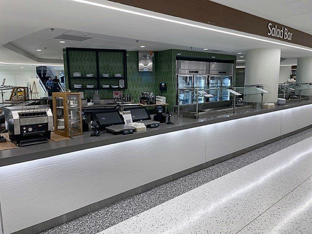 A long counter in a restaurant with a sign that says salad bar.