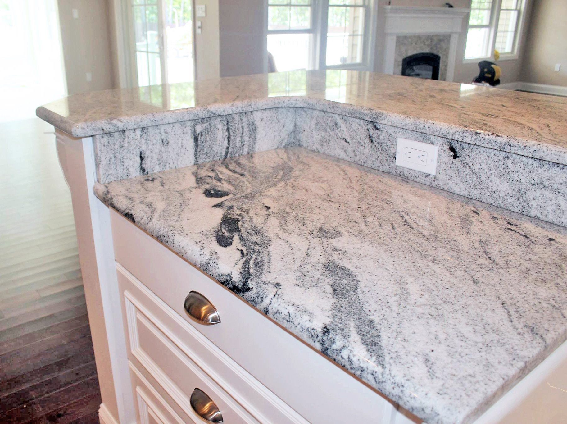 A kitchen with a granite counter top and white cabinets