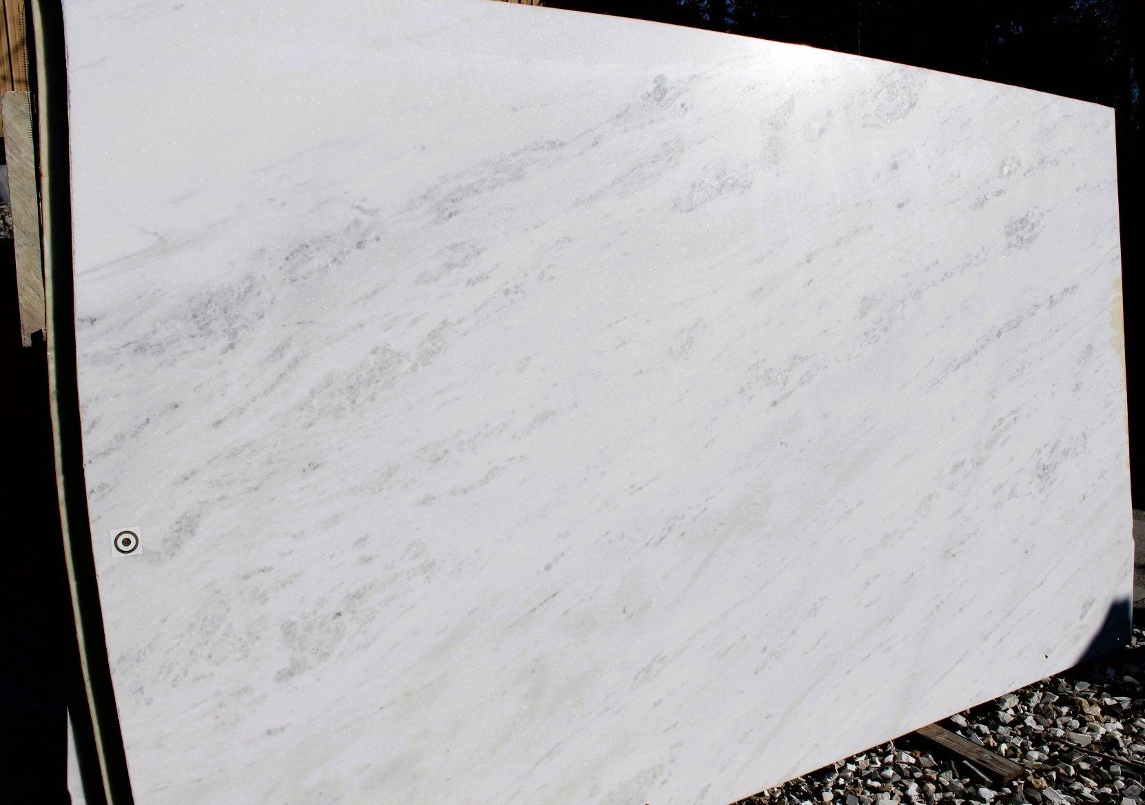 A white marble slab is sitting on a pile of gravel.