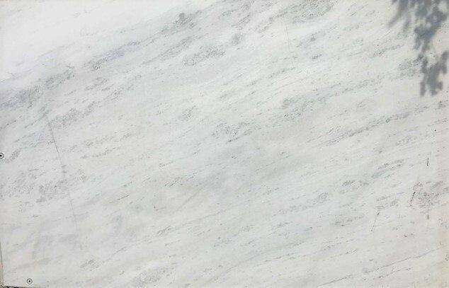 A close up of a white marble slab with a tree shadow on it.