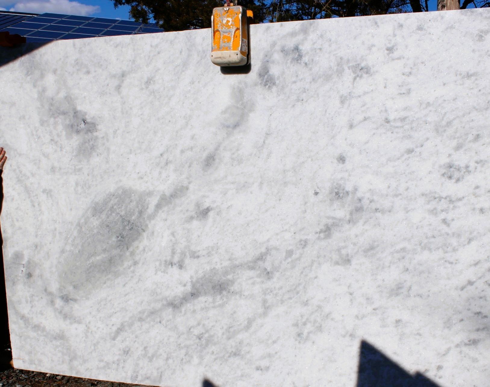 A large white marble slab is sitting on top of a concrete surface.