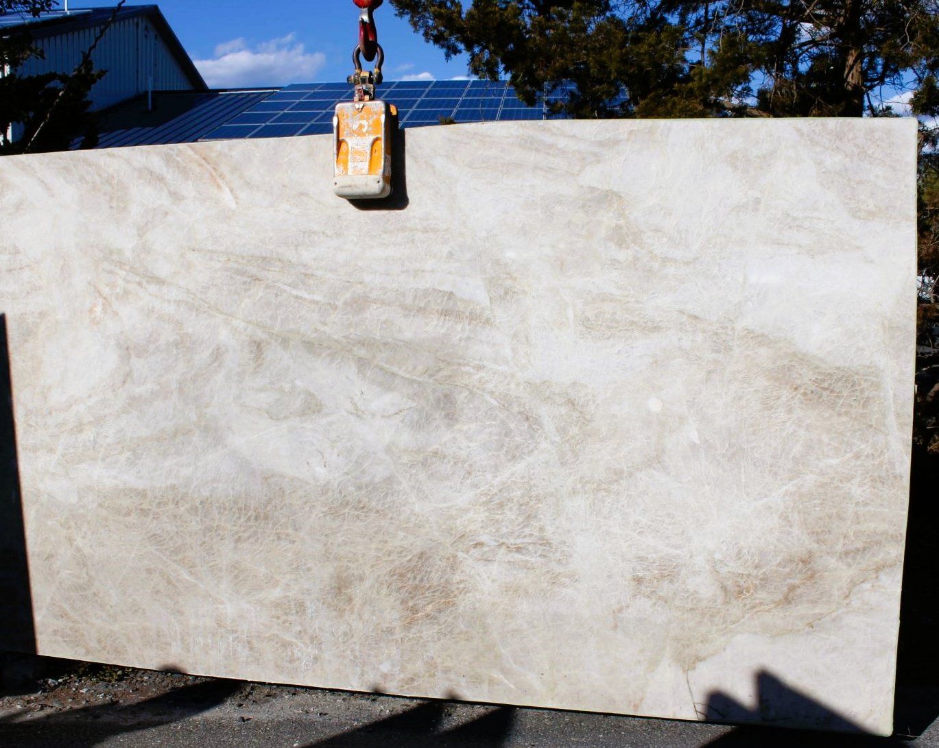 A large slab of granite is being lifted by a crane