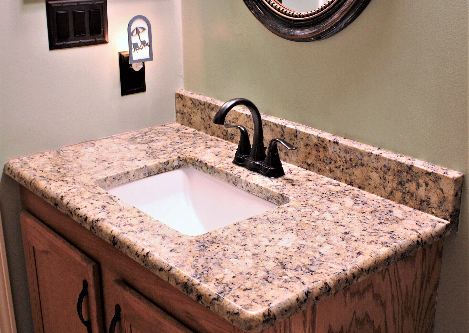 A bathroom sink with a granite counter top and a mirror