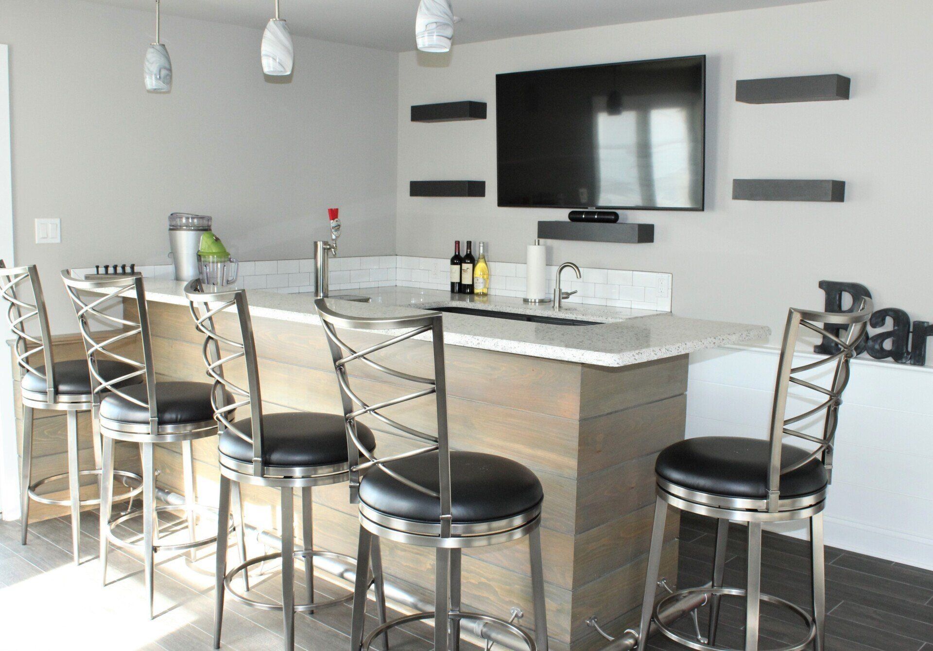 A bar with stools and a flat screen tv on the wall