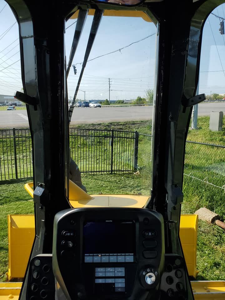 The inside of a yellow tractor with a fence in the background