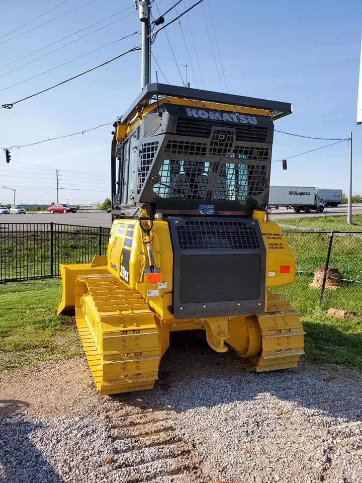 A yellow komatsu bulldozer is parked in a gravel lot.