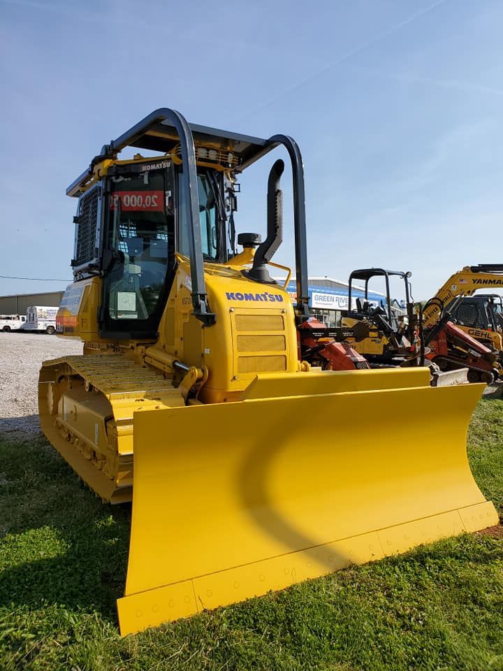 A yellow bulldozer is parked in a grassy field.