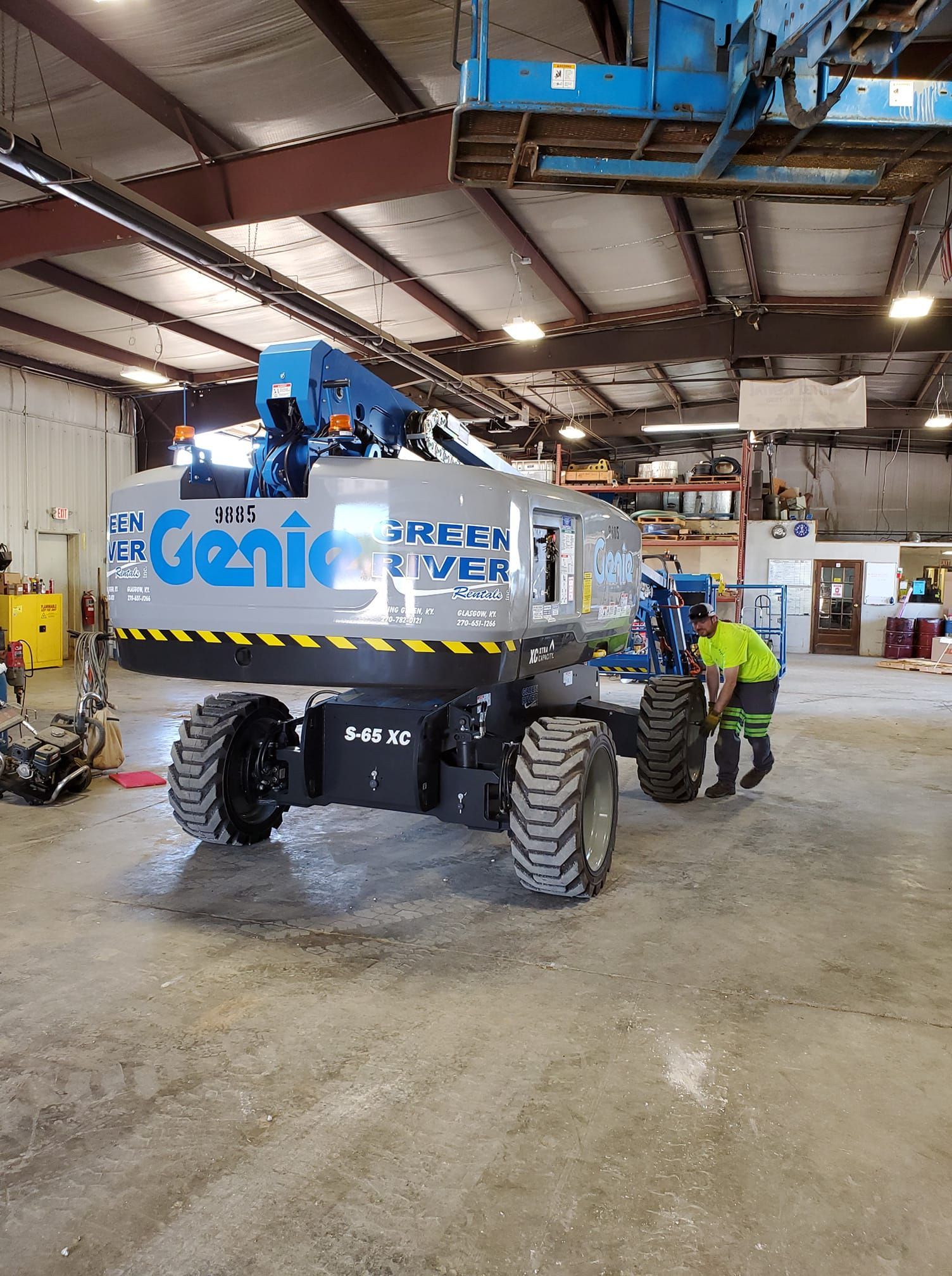 A man is working on a genie lift in a garage.