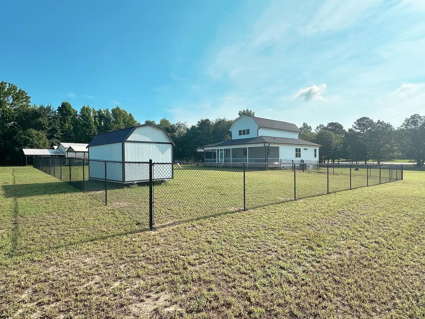 There is a barn and a fence in the middle of a field.