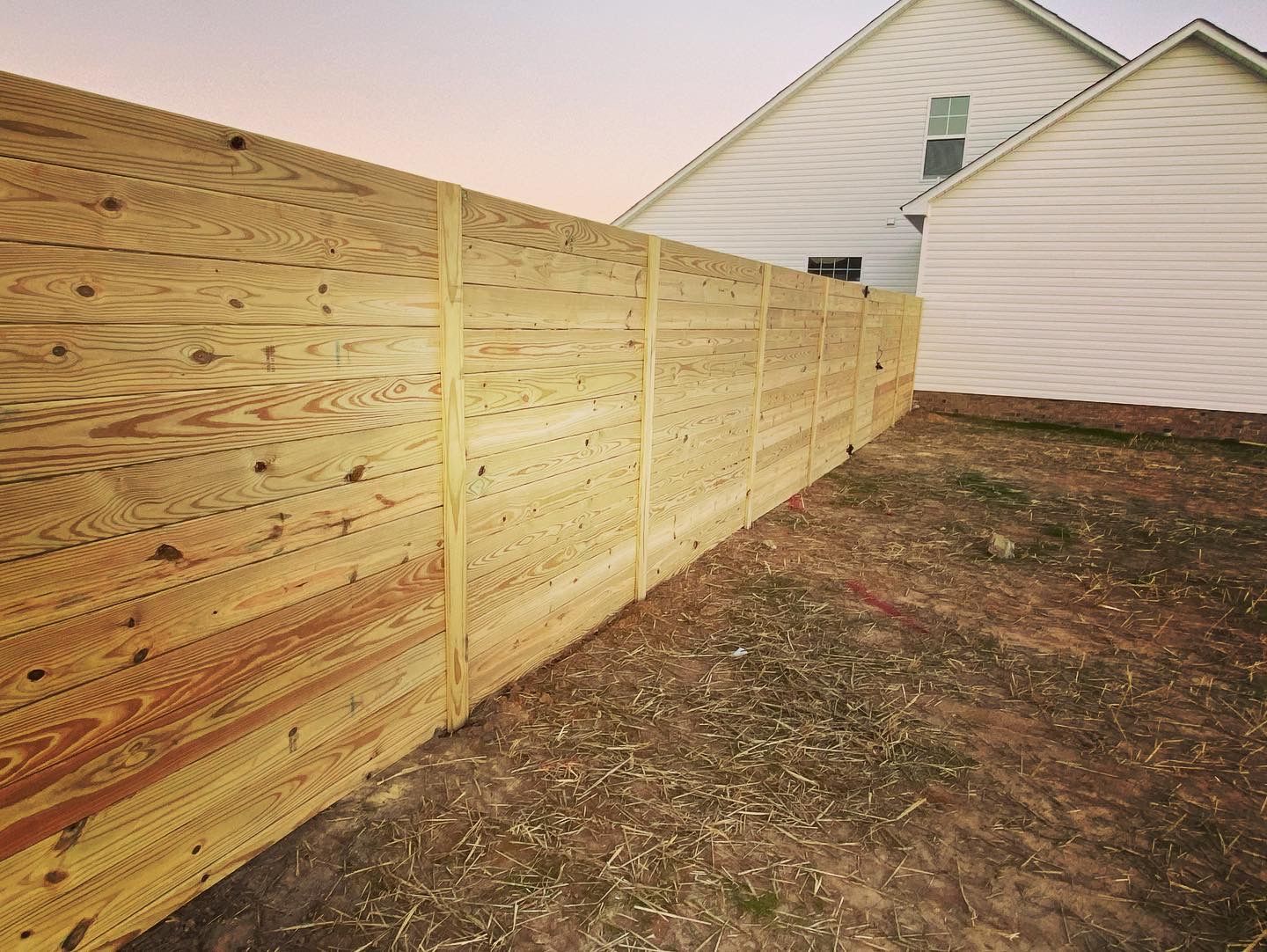 A wooden fence is in the backyard of a house.