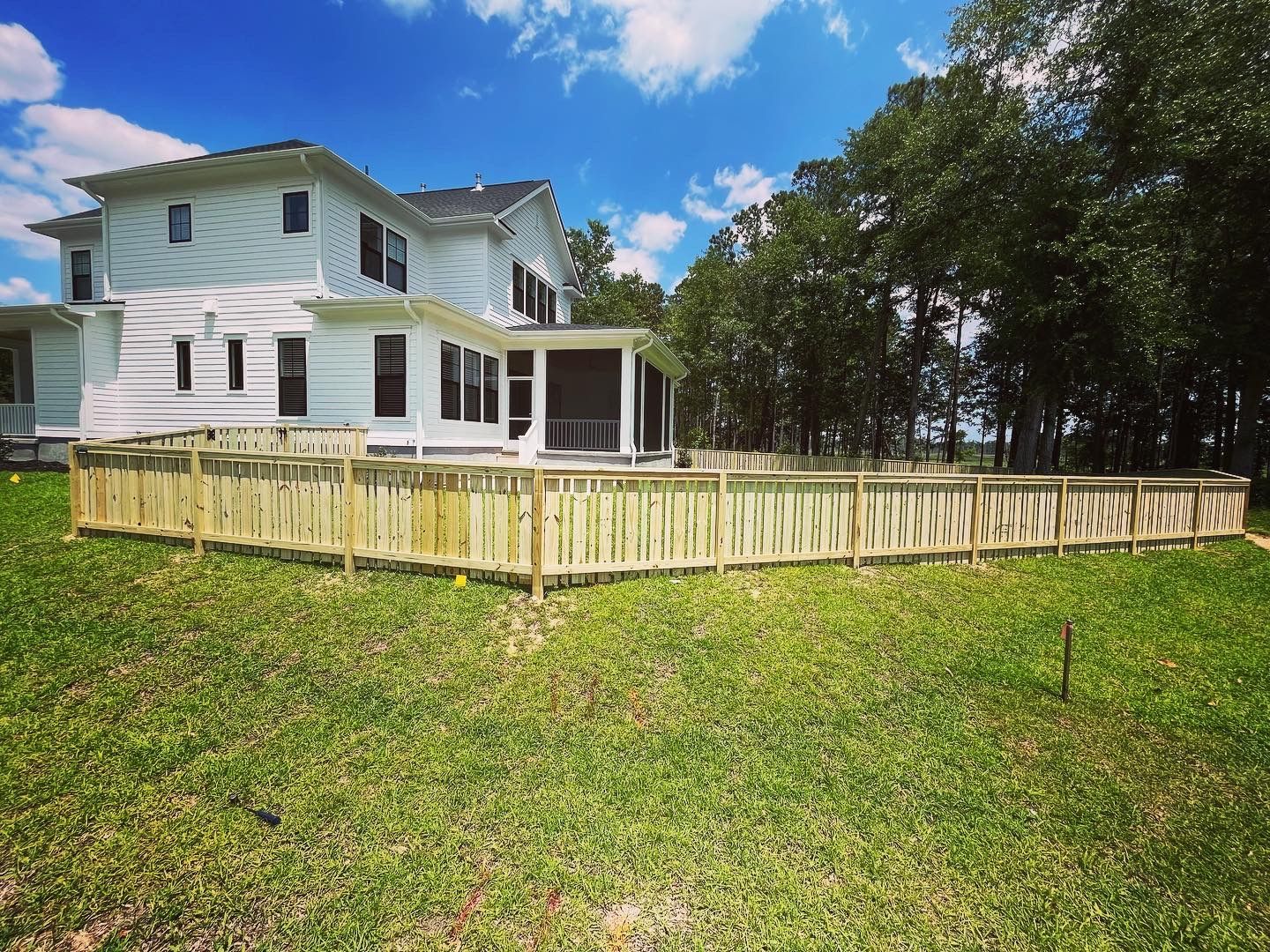 A large white house with a wooden fence in front of it.