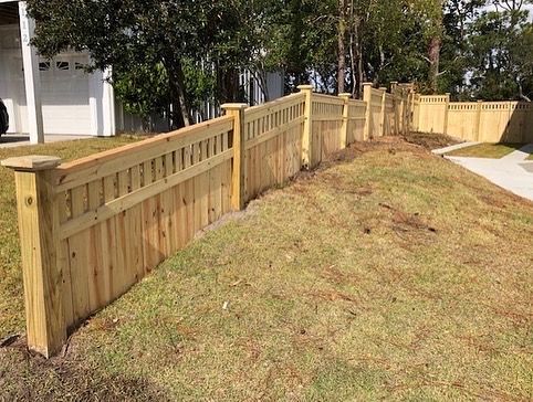 A wooden fence is sitting on top of a lush green lawn in front of a house.