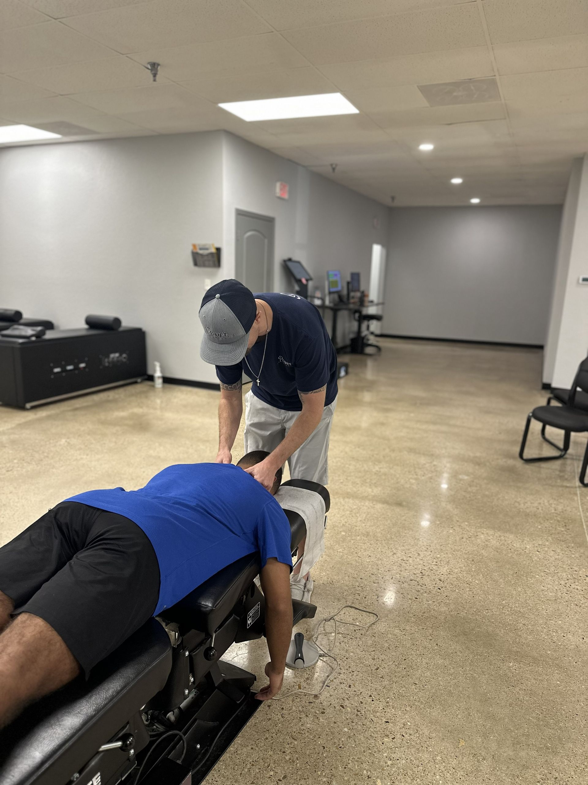 Therapist adjusts a client on a treatment table in a rehab clinic room