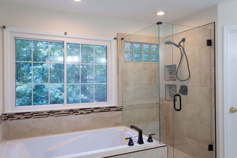 A bathroom with a tub , shower , and window.