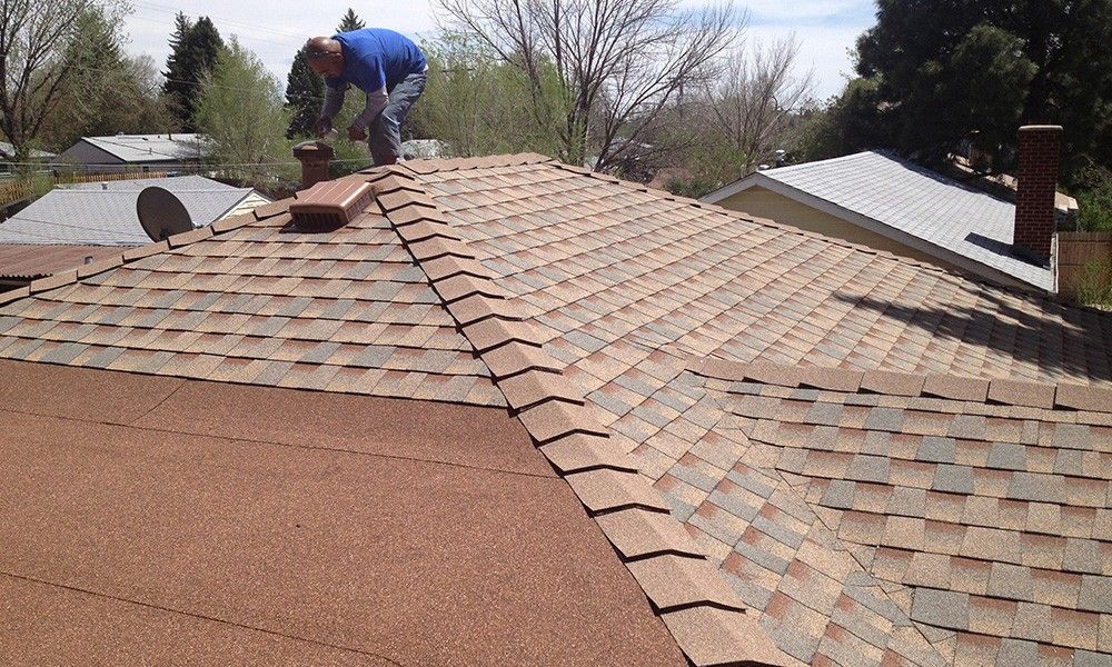A man is working on the roof of a house.