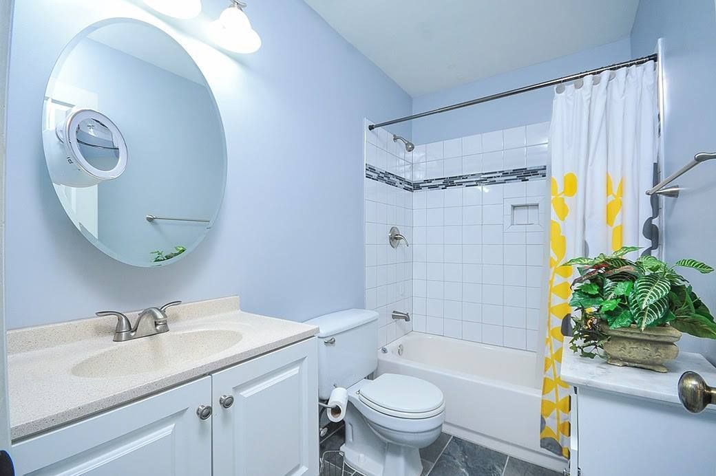 A bathroom with a toilet , sink , shower and curtain.