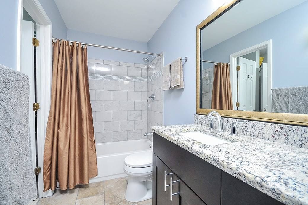 A bathroom with a sink , toilet , shower and mirror.