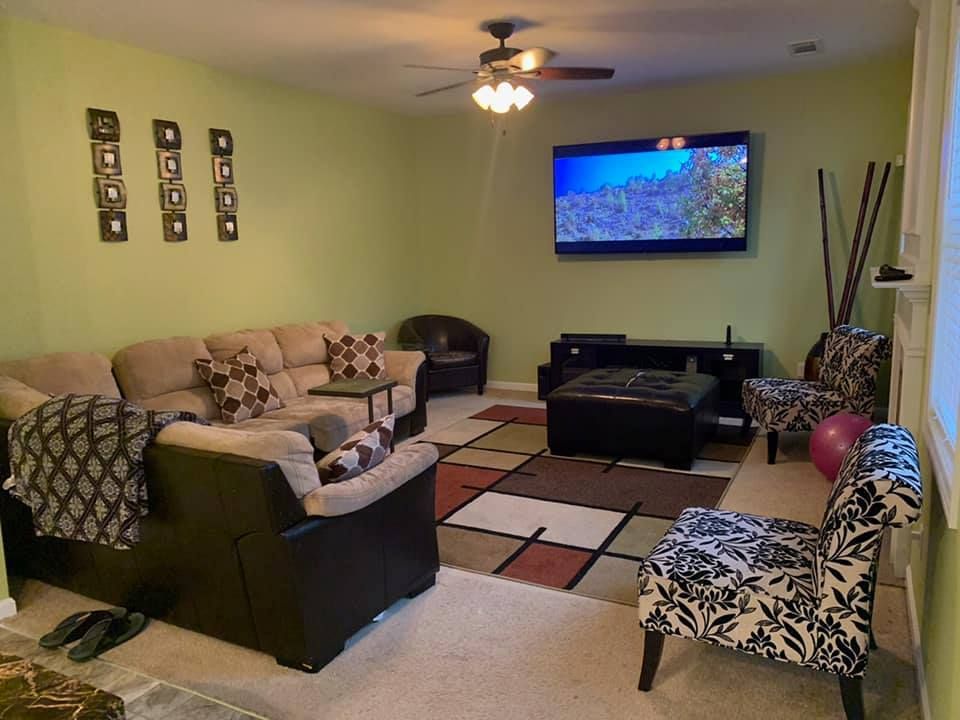 A living room with a couch , chairs , and a flat screen tv.