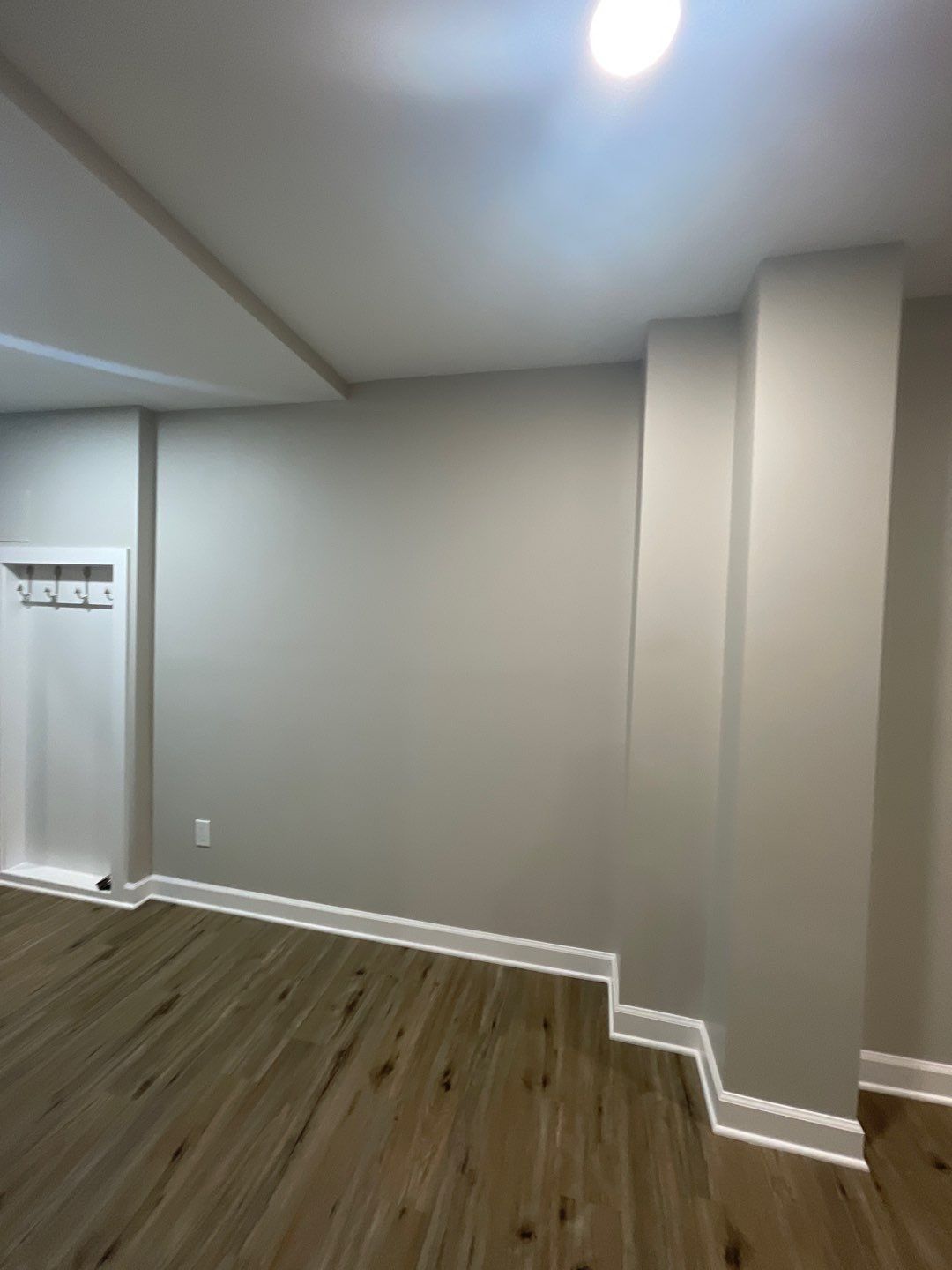 An empty basement room with white walls and wooden floors