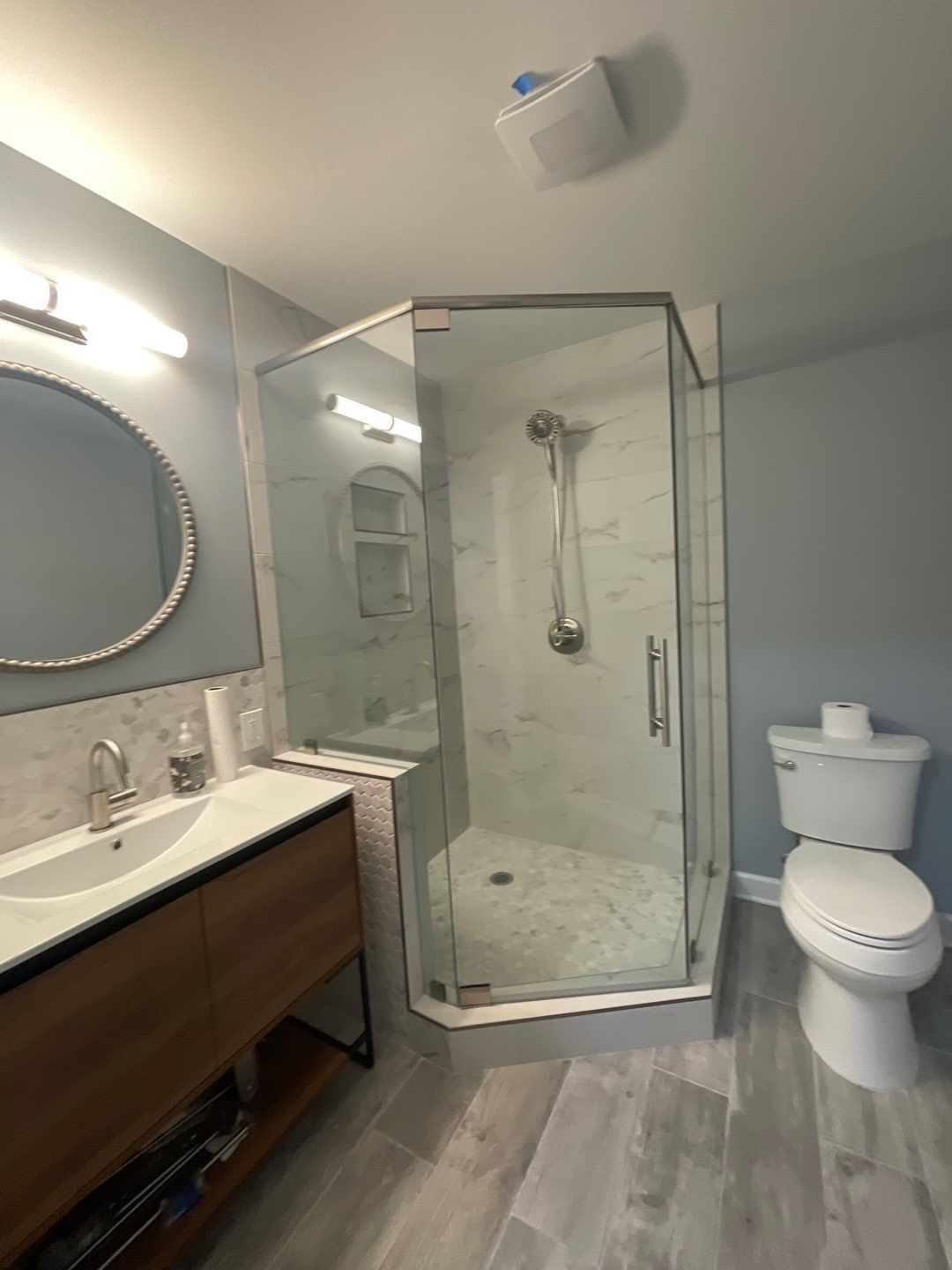 Remodeled bathroom with a toilet, sink, shower, and mirror