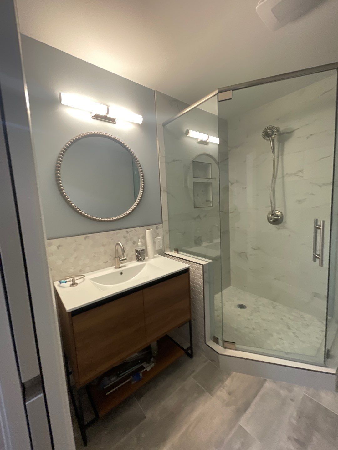 Remodeled bathroom with a sink, mirror, and walk-in shower.