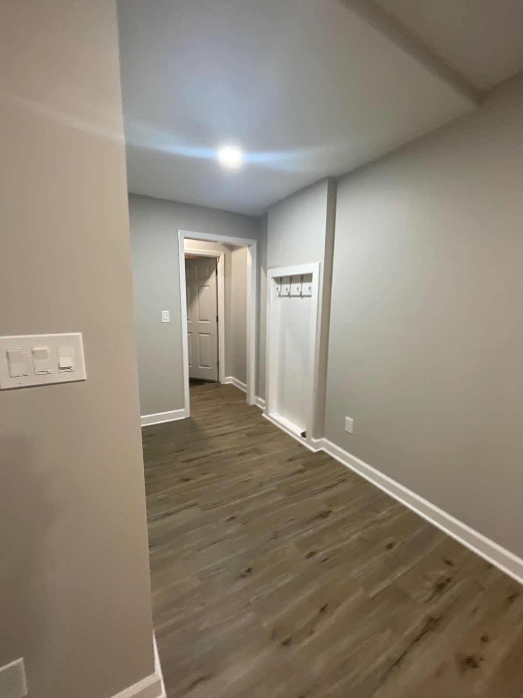 A hallway with hardwood floors and gray walls
