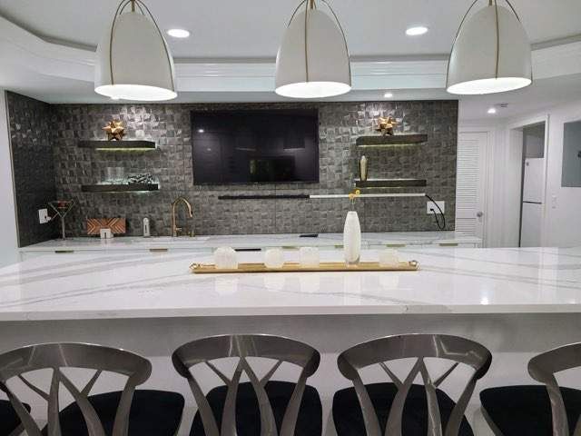 A remodeled kitchen with a large countertop and chairs