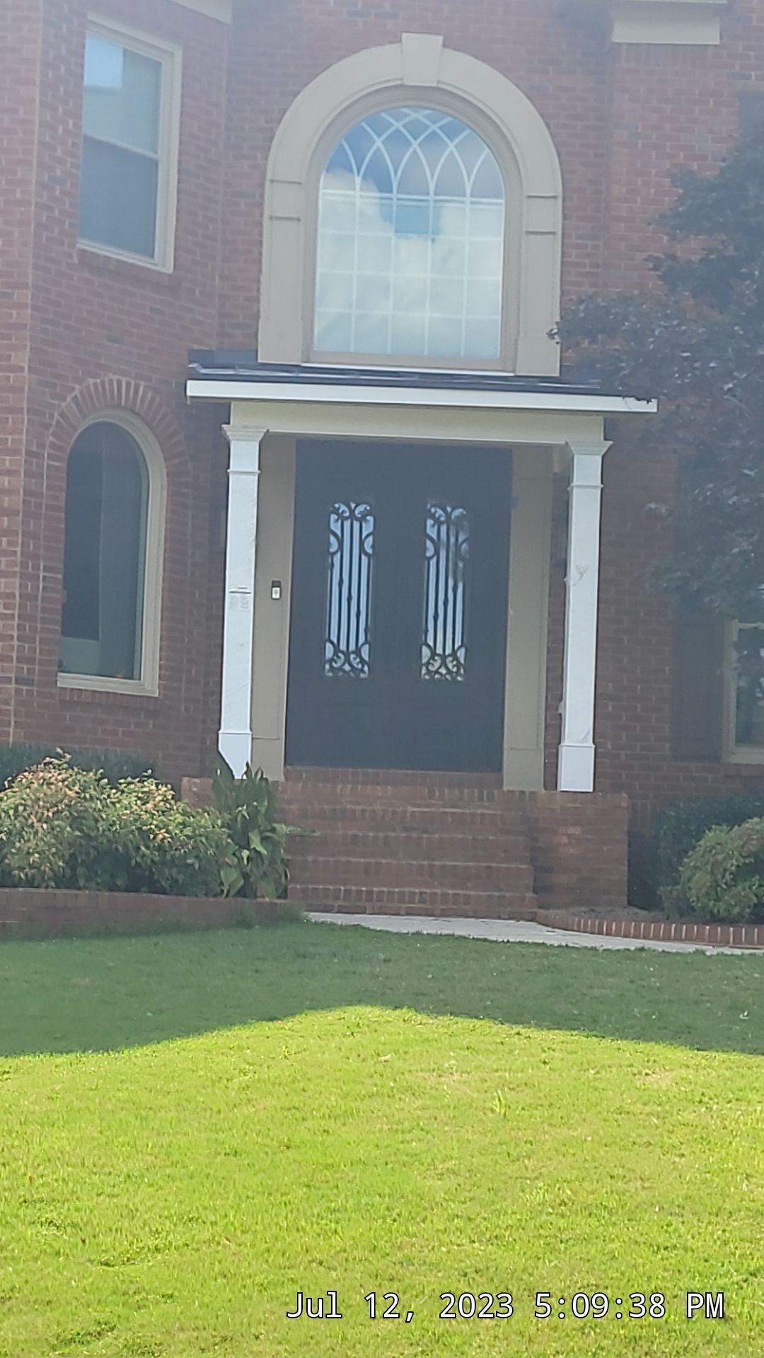 A large brick house with a black door and a white porch