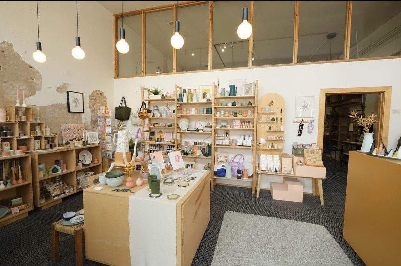 Interior view of a well-lit retail store with wooden shelves displaying various merchandise.