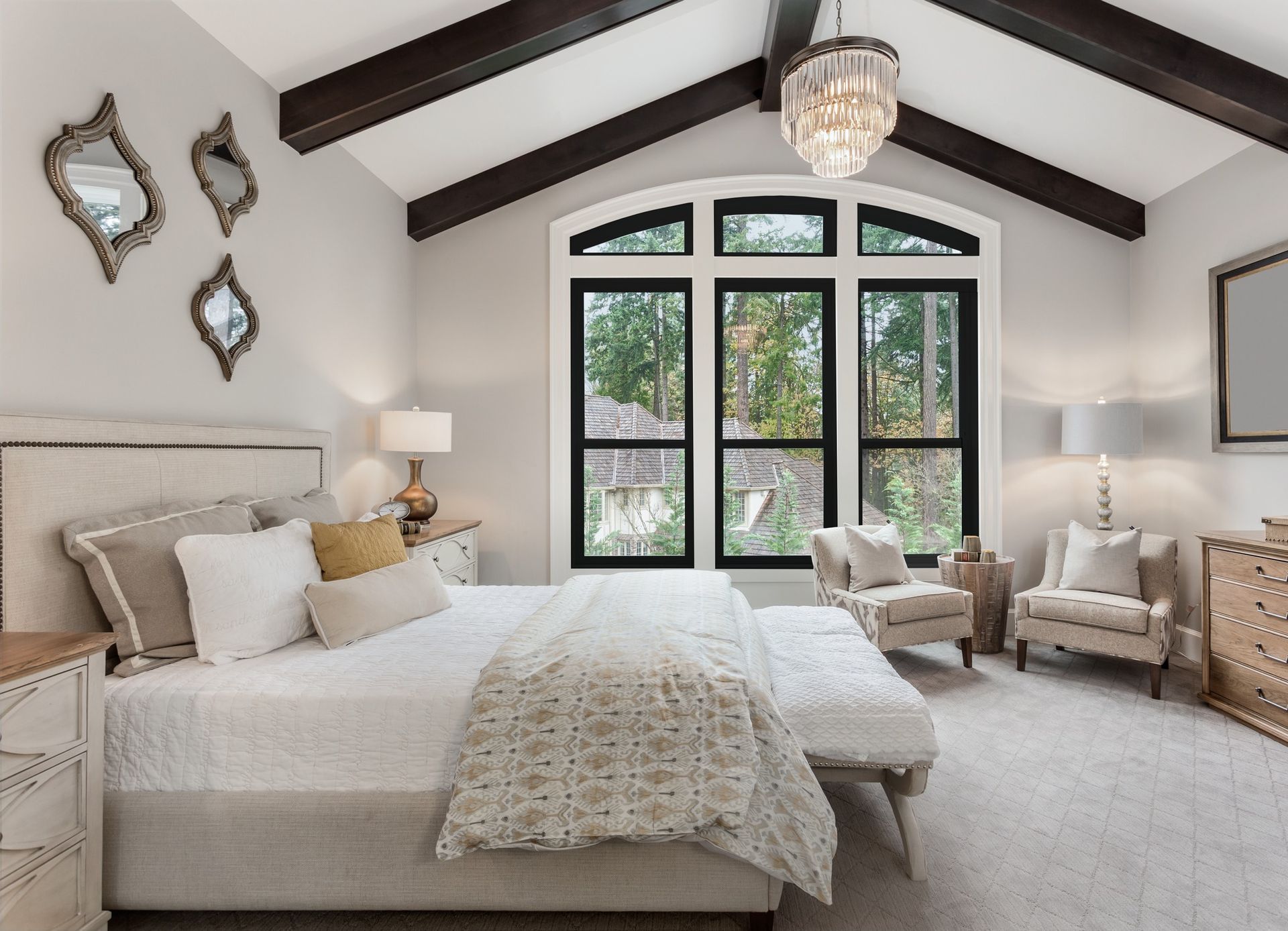 Bedroom with large window, vaulted ceiling, and bed with decorative pillows and blanket.
