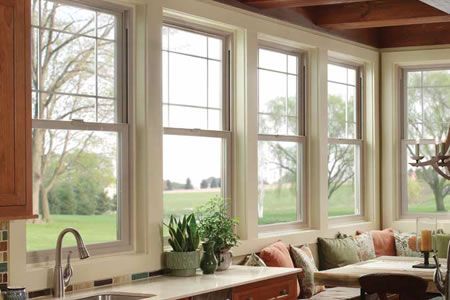Row of vertical windows overlooking a green landscape in a kitchen setting.