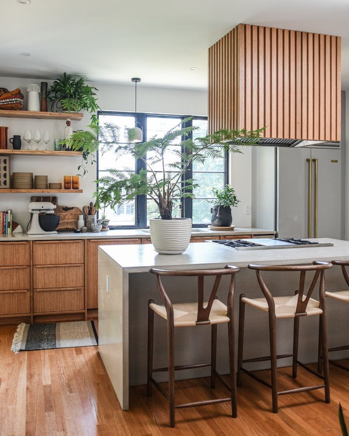 Stylish kitchen with wooden cabinets, island, and large window; accented with plants.