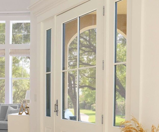 Cream-colored French doors with arched window panes; view of a green tree and lawn outside.