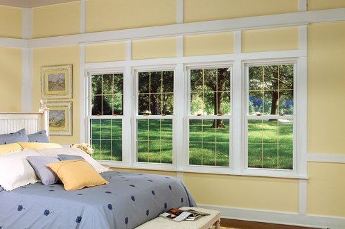 Bedroom with a bed, four windows overlooking a green lawn, and yellow walls.