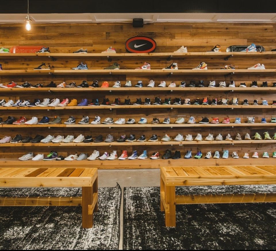 Sneaker store display: wooden shelves with rows of colorful shoes, benches in front.