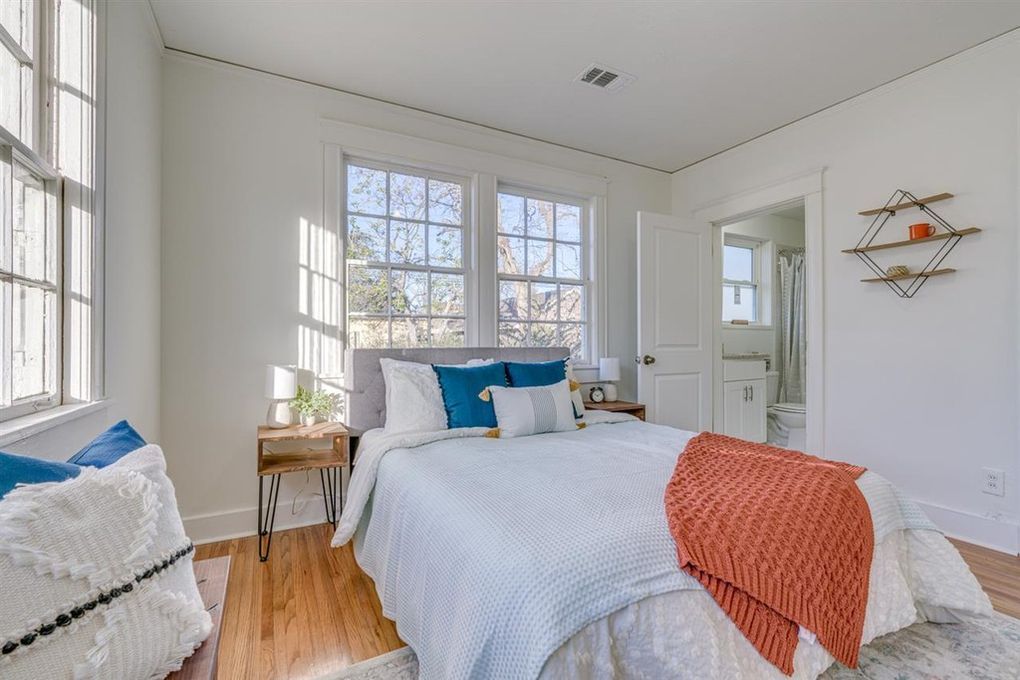 Bedroom with white walls, windows, and bed with blue and orange accents.
