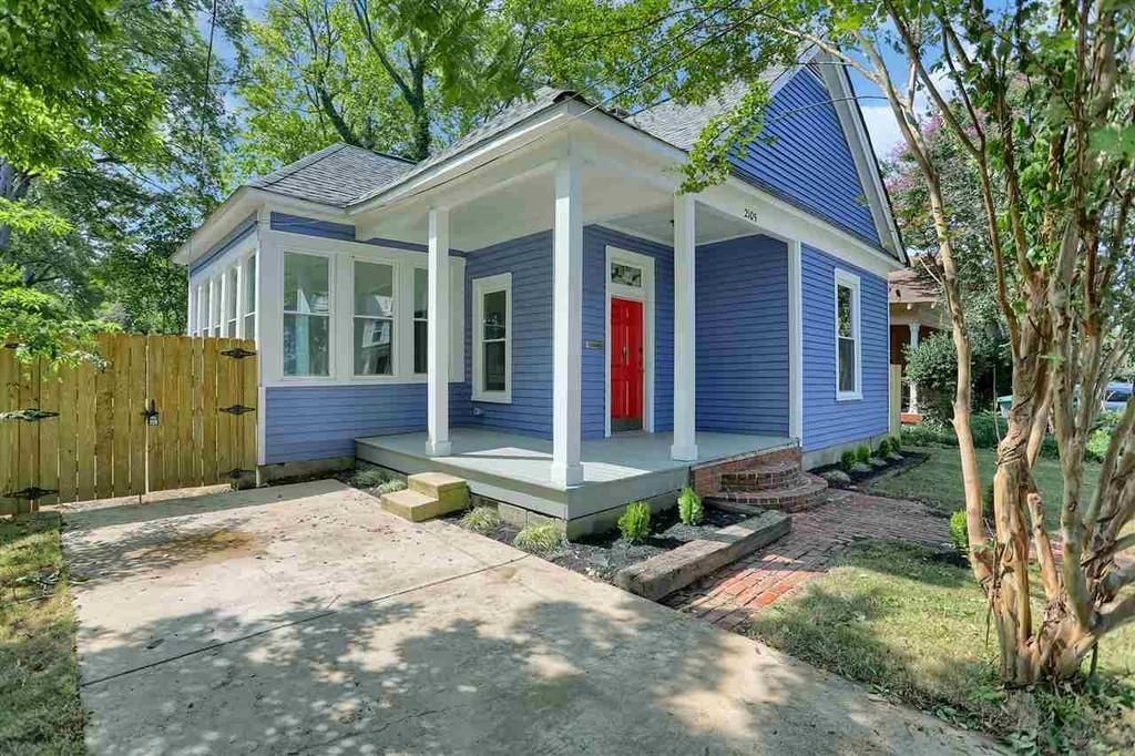 Blue house with red door and white columns, front porch. Driveway and small yard.