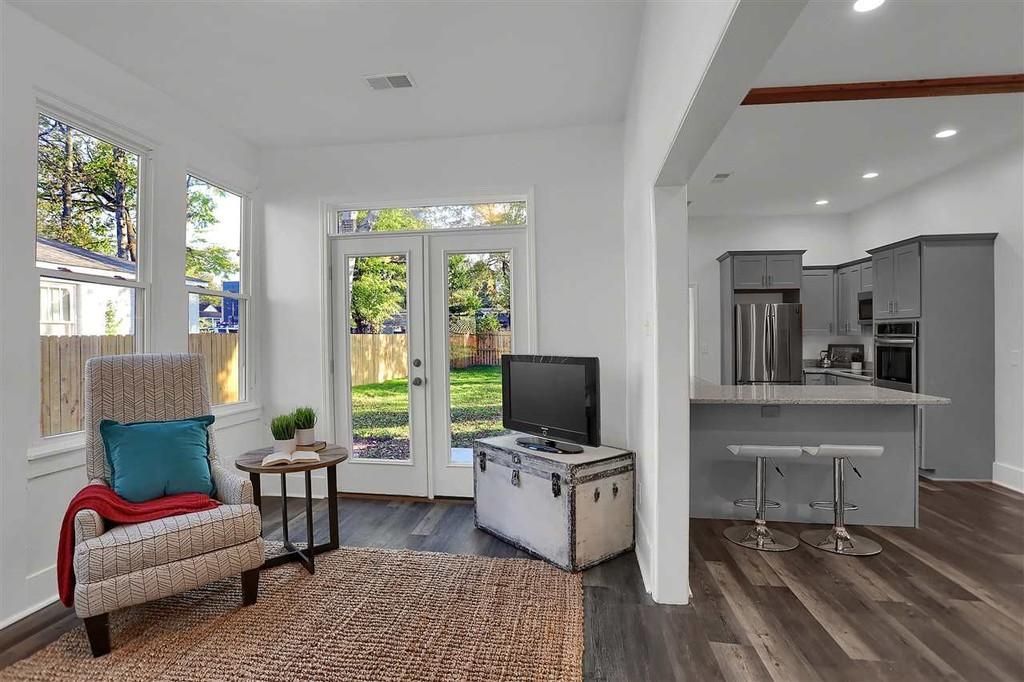 Living room with chair, rug, trunk-TV stand, and open view to kitchen.